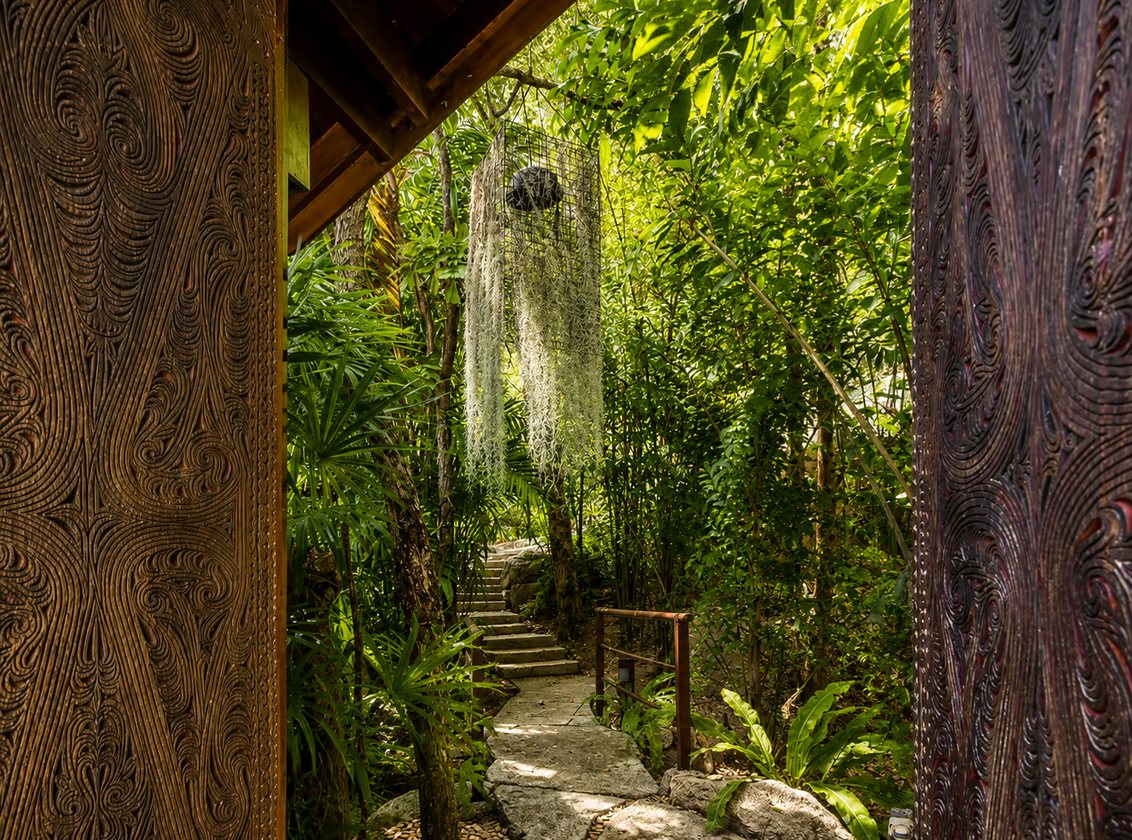 Carved wooden doors opening to a jungle path
