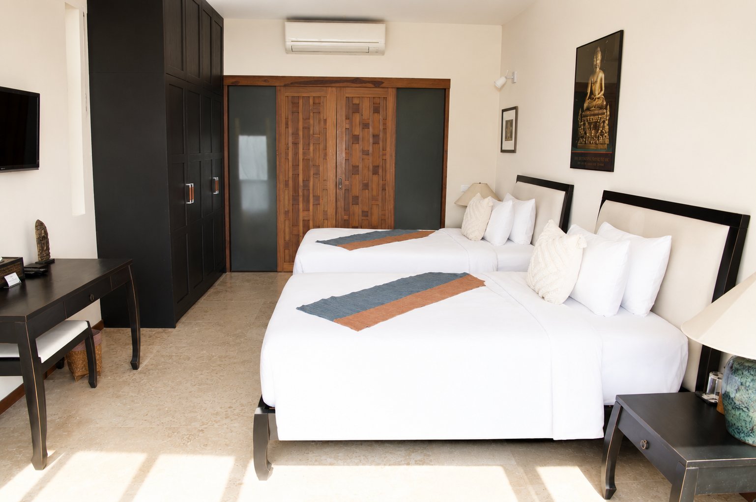Poolside suite bedroom with twin beds and carved teak wardrobe